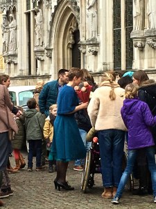 The bride is in blue, holding a bouquet of pink flowers. 