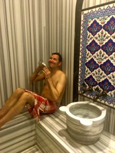 Matthew looks like he's trying really hard to enjoy the experience. The way it works is that you crank up the heating elements behind the walls, turn on the shower to add steam, and then douse yourself with hot water from the sink.